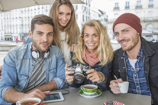 group of friends in coffee shop looking picture at vintage camera