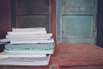 Books on the wooden table in the old library. Selective focus with blurred wooden background.