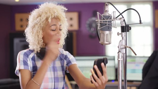  Female vocalist in recording studio using mobile phone for video call