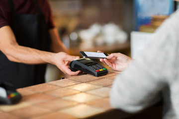 hands with payment terminal and smartphone at bar