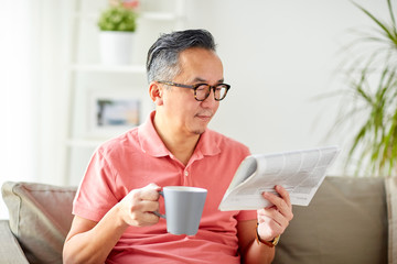 man drinking coffee and reading newspaper at home