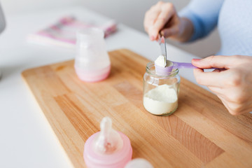 Obraz na płótnie Canvas hands with jar and scoop making formula milk