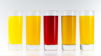 Glasses filled by colorful fruit juices on white background