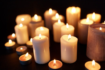 Fototapeta na wymiar candles burning in darkness over black background