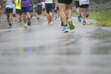 back man Marathon runners focus clear running shoes on the street with rain.