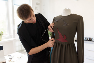 fashion designer with dummy making dress at studio