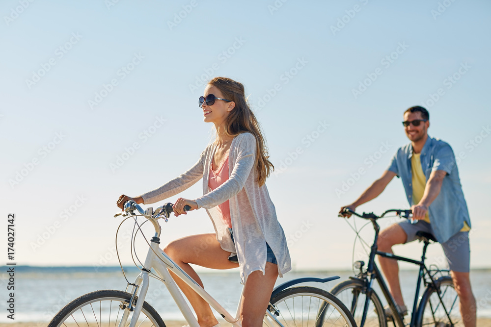 Poster happy young couple riding bicycles at seaside