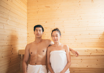 Young couple relaxing inside a sauna for cleaning and refreshing the body at spa resort hotel luxury