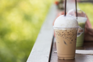 Close up ice cappuccino on wooden table with green nature background