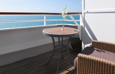 Luxury cruise ship balcony with white orchid flower on wooden table.