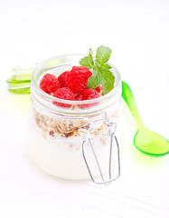 healthy breakfast: yogurt with muesli and raspberries on a black background