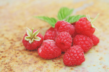 Ripe raspberry with a leaf on an old metal background