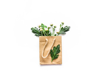Floral composition. Buds and leaves in paper bag on white background top view copyspace