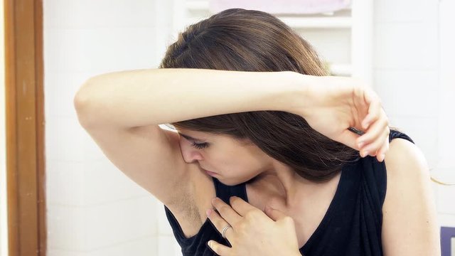Beautiful woman making funny expressions smelling stinky armpit slow motion 4K