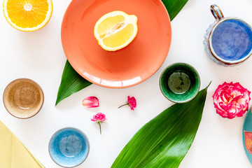 Crockery pattern. Cups and plates near tropical leaves and fruits on white background top view