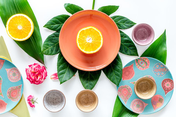 Crockery pattern. Cups and plates near tropical leaves and fruits on white background top view