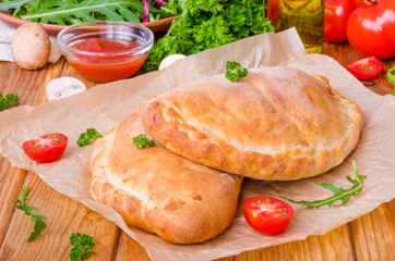 Pizza Calzone with tomato sauce, cheese, herbs, mushrooms and sausages