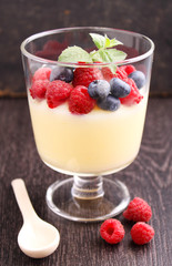 Milk pudding with berries in a glass on a black background