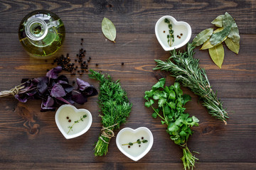 natural oil and fresh greenery for restaurant cooking on wooden kitchen table background top view