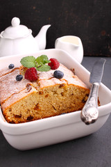 homemade cake decorated with raspberries and blueberries on a black background