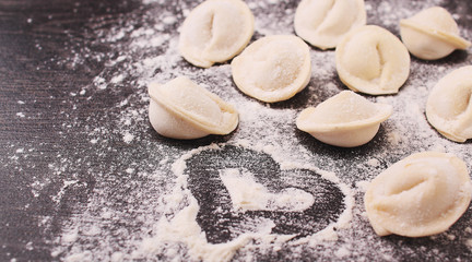 Fototapeta na wymiar Raw dumplings in flour on a black background.copy space.