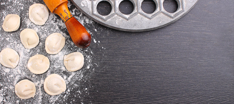 rolling pin, raw dumplings in flour on a black background.copy space.