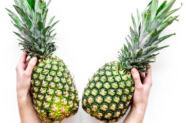 Tropical fruits background. Hand hold pinneapple on white top view copyspace