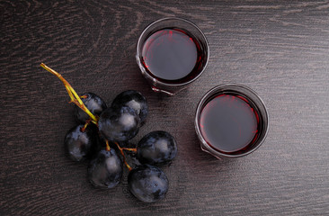 ripe grapes, red wine and a glass on a black background