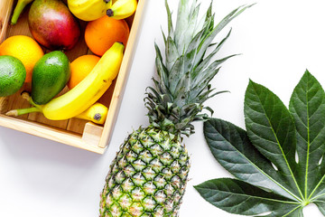 Sell friuts on the market. Bananas, oranges, mango in box and pineapple on white background top view