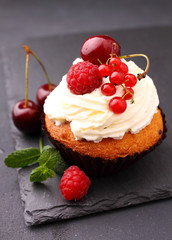 homemade cupcake with a cream, decorated with mint and berries on a black background.