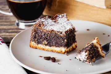sweets and desserts, pastries, delicious chocolate cake with poppy seeds, raisins and powdered sugar with a cup of black coffee on a dark wooden background