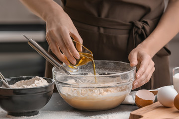 Female chef making dough in glass bowl on kitchen table
