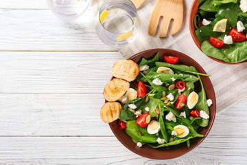 Plate of tasty salad with spinach leaves  on wooden table