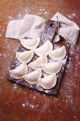 dumplings (varenili) with potato sprinkled with flour on a wooden old board