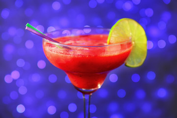 Glass of delicious strawberry daiquiri against defocused lights