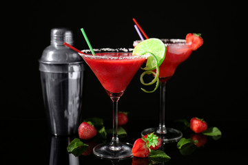 Glasses of delicious strawberry daiquiri on black background