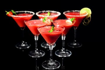 Glasses of delicious strawberry daiquiri on black background