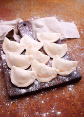 dumplings (varenili) with potato sprinkled with flour on a wooden old board