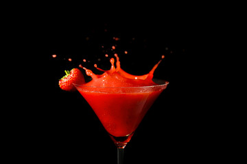Glass of delicious strawberry daiquiri with splash on black background
