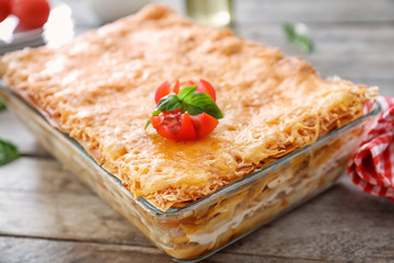Tasty lasagna in baking dish on wooden table