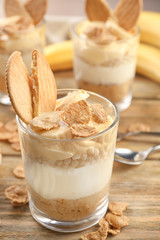 Glass with delicious banana pudding on table