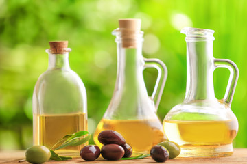 Healthy olives and bottles of oil on blurred background