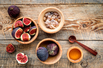 Make jam. Fresh blue figs in bowl, sugar and honey on wooden background top view