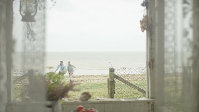  Romantic young couple embracing at beach house & looking out at the view