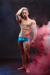 Strong athletic young man with huge muscles posing at studio, vertical image