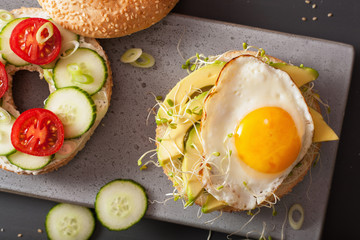 sandwiches on bagels with egg, avocado, soft cheese, tomato, cucumber, alfalfa sprouts