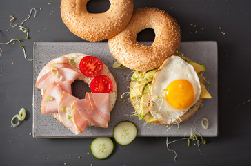 sandwiches on bagels with egg, avocado, soft cheese, alfalfa sprouts, ham, tomato