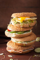 variety of sandwiches on bagels: egg, avocado, ham, tomato, soft cheese, alfalfa sprouts