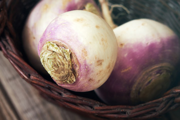 Closeup of raw organic turnips in rustic woven basket - obrazy, fototapety, plakaty