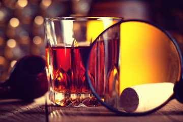 Glass of whiskey, magnifying glass and cork